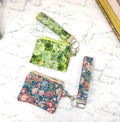 Two floral-patterned zipper pouches with keychains on a marble surface.