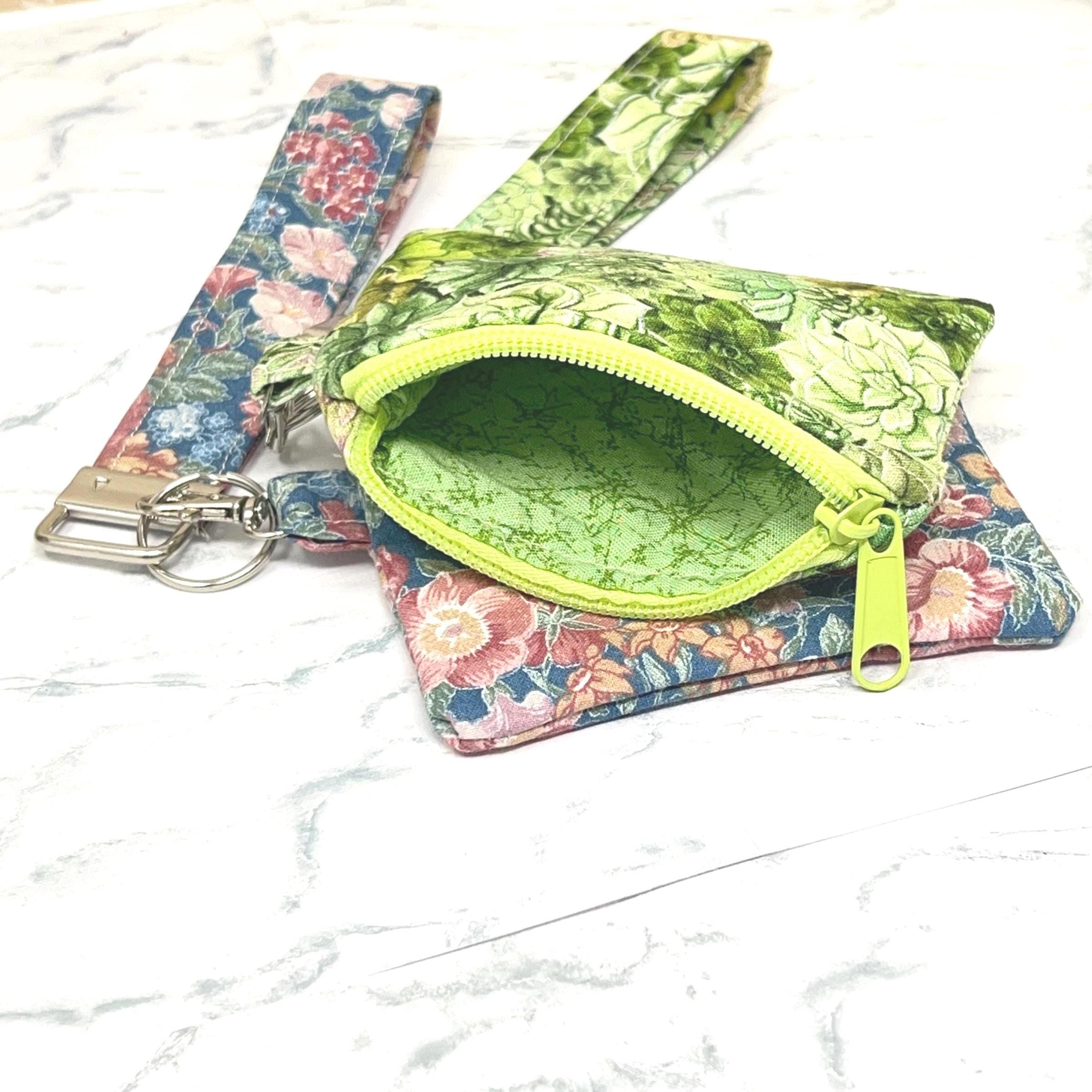 Floral-patterned zipper pouch with a coordinating green interior lining and matching wristlet key chain.
