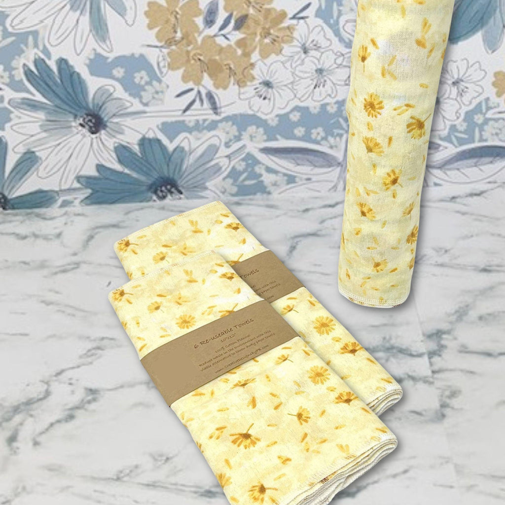 Flannel reusable paper towels. This pictures shows possible display options on Kitchen counter. One group is folded in a basket and the other group rolled on a cylinder. place setting. Cotton fabric has yellow and gold dandelions  on a soft yellow on background