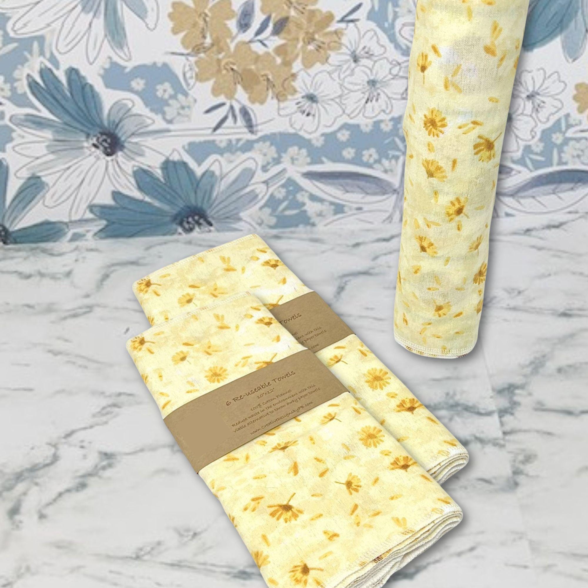 Flannel reusable paper towels. This pictures shows possible display options on Kitchen counter. One group is folded in a basket and the other group rolled on a cylinder. place setting. Cotton fabric has yellow and gold dandelions  on a soft yellow on background