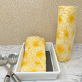 Flannel reusable paper towels. This pictures shows possible display options on Kitchen counter. One group is folded in a basket and the other group rolled on a cylinder. Cotton fabric has a large overlapping  sketch of yellow daisies 