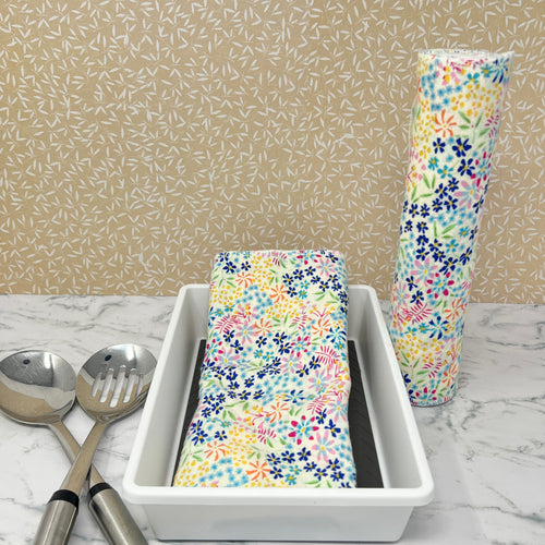 Flannel reusable paper towels. This pictures shows possible display options on Kitchen counter. One group is folded in a basket and the other group rolled on a cylinder. Cotton fabric has a ditzy floral print pattern of tiny colorful flowers on a white background