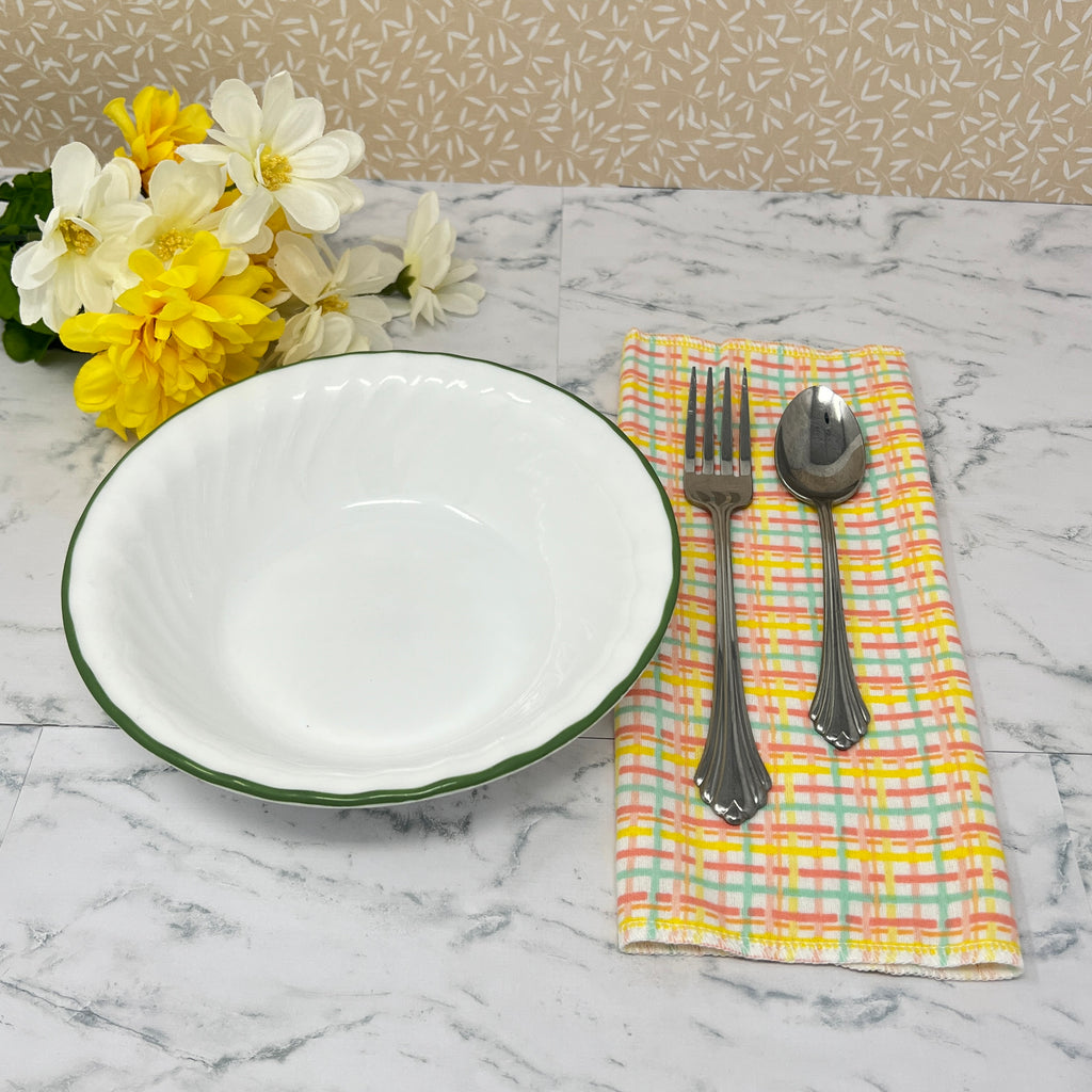 Flannel reusable paper towels. This pictures shows possible use as a napkin in a place setting.  Cotton fabric has a yellow, turquoise and light red plaid pattern on a white background