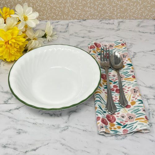 Flannel reusable paper towels. this pictures shows one towel in a place setting.   Fabric has a floral and greenery  pattern in a painted "style" with red and gold flowers, and greenery on a white background.