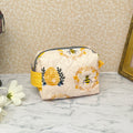 Small quilted pouch with a zipper top and handle. Fabric is cream color with honey bees and a bee hive. handle and lining are yellow