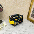 small quilted cosmetic bag with zipper and handle. Fabric is a colorful assortment of butterflies and feathers on a black background with a yellow handle and liner