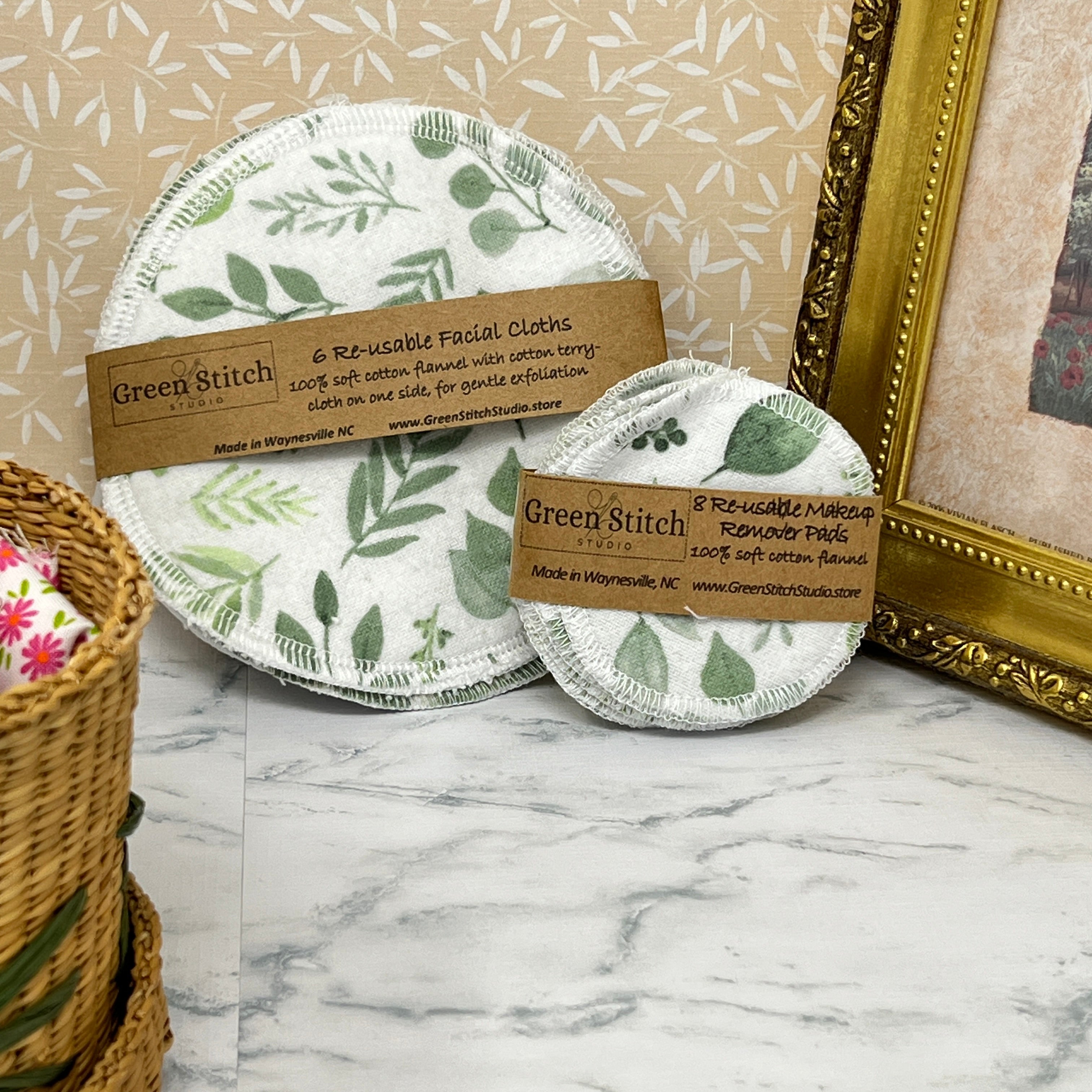 Reusable facial cloths with green leaf pattern on a marble surface, branded 'Green Stitch'.